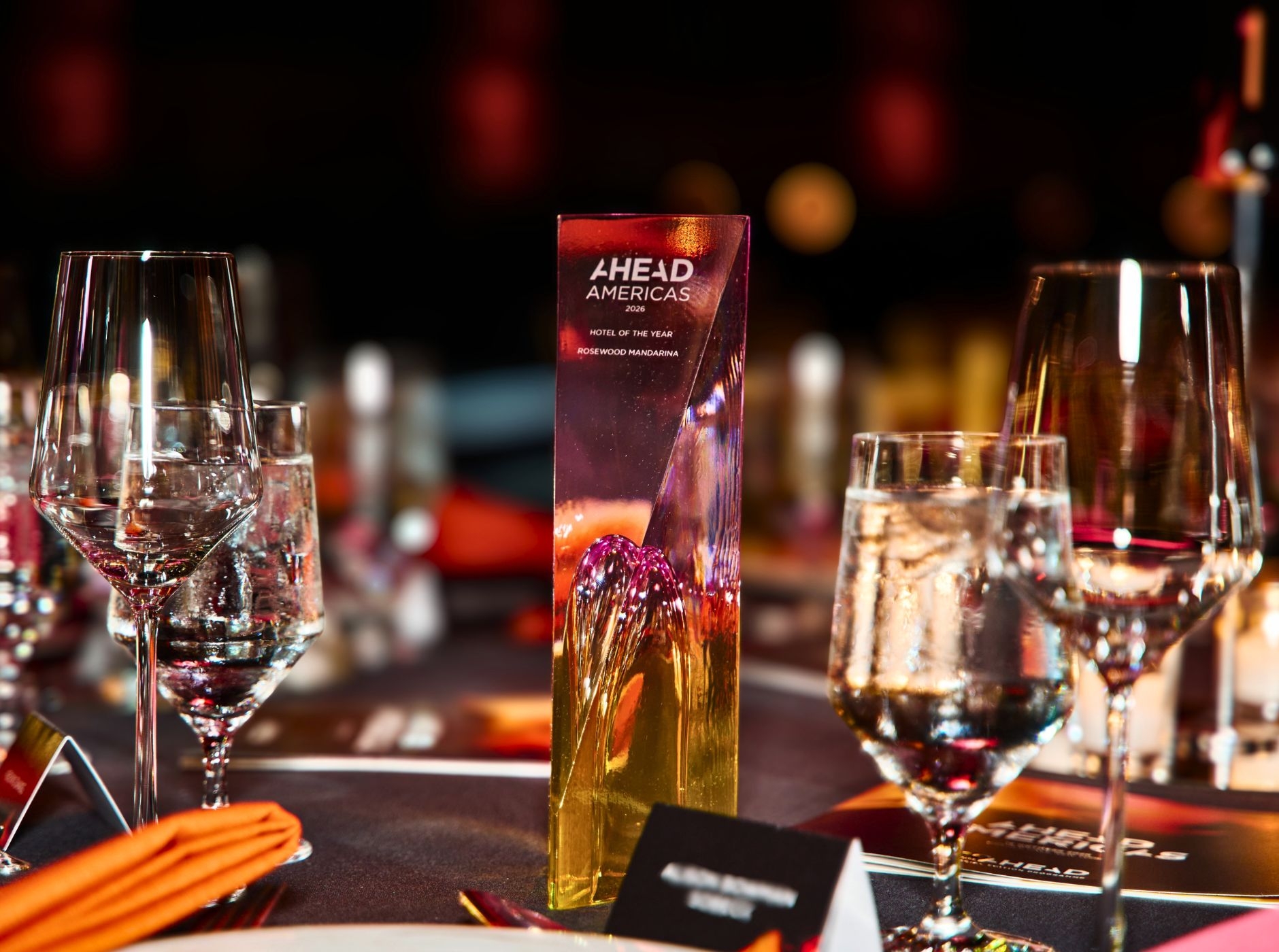 AHEAD Americas trophy among glasses on a festive table for hospitality awards.