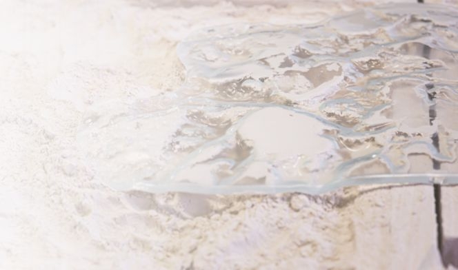 A glass surface with delicate texture and transparent water droplets.
