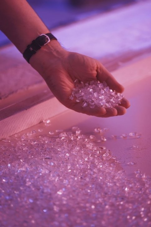 Hand holding clear crystals against a colorful background.