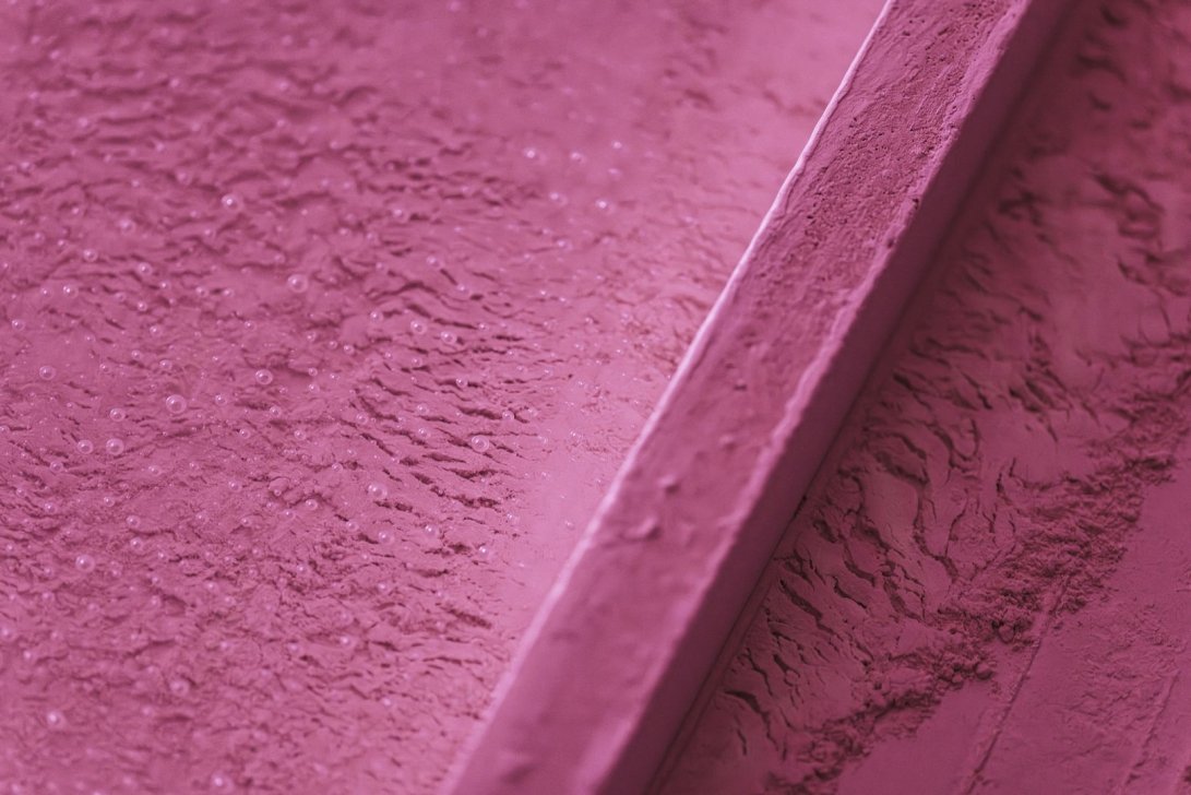 Textured pink surface with subtle details and bubbles.