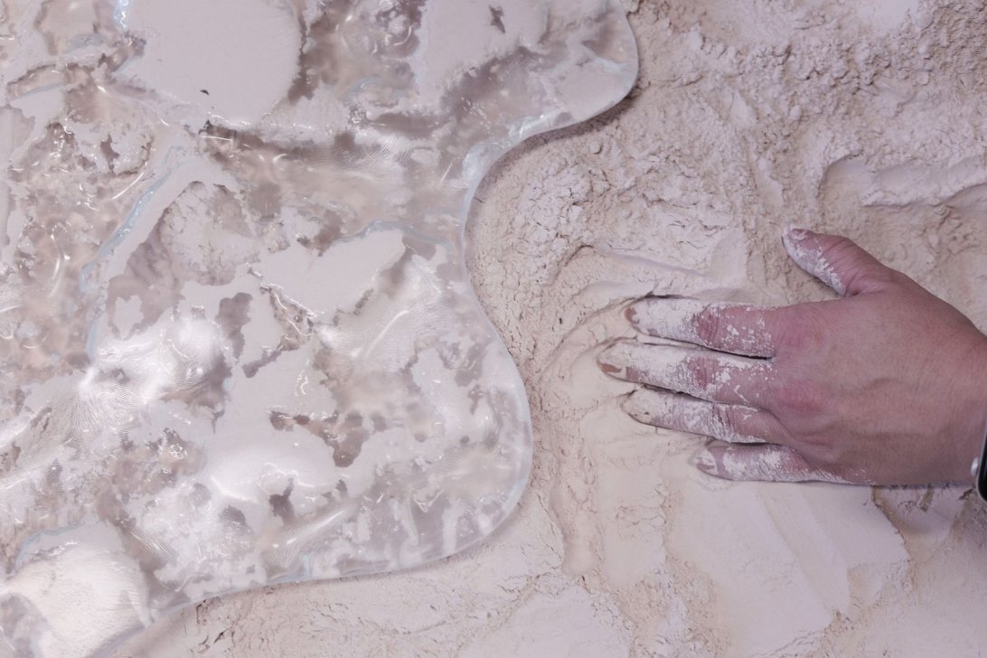 Hand mixing light substance on a glossy, smooth surface.