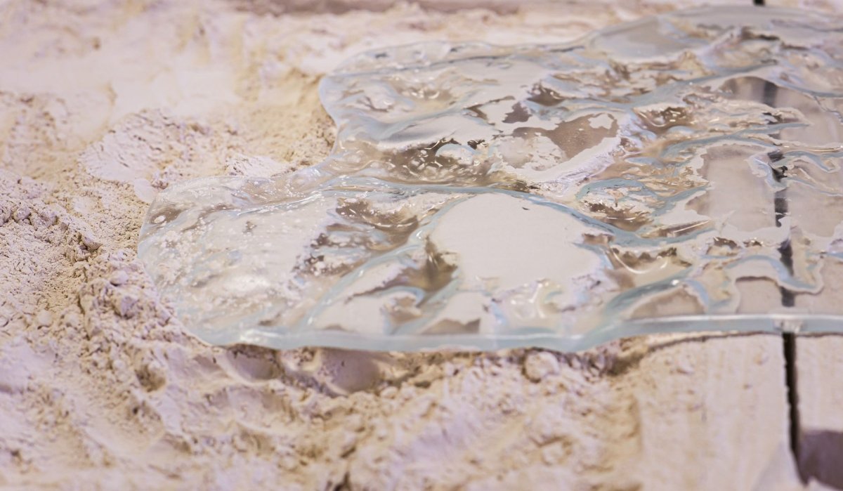 Transparent material on a sandy surface with intricate details and texture.