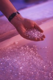Hand holding clear crystals against a colorful background.