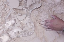 Hand mixing light substance on a glossy, smooth surface.