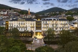Elegantní hotel s moderní architekturou obklopený přírodou a městskou krajinou.