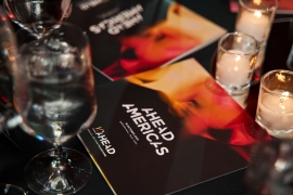 AHEAD Americas program on the table, illuminated by candles and glasses of water.